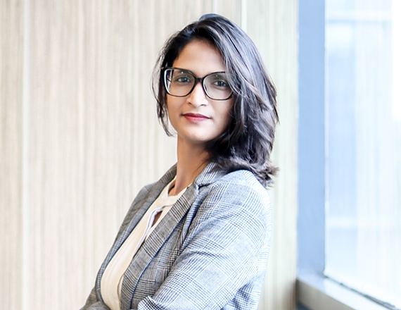 Khushboo Oswal: A woman stands in a business outfit in an office environment.
