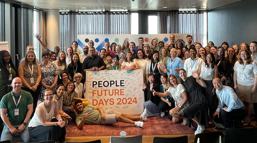 A large crowd standing together and smiling at the camera, with a large sign in the middle saying 'People Future Days 2024'.